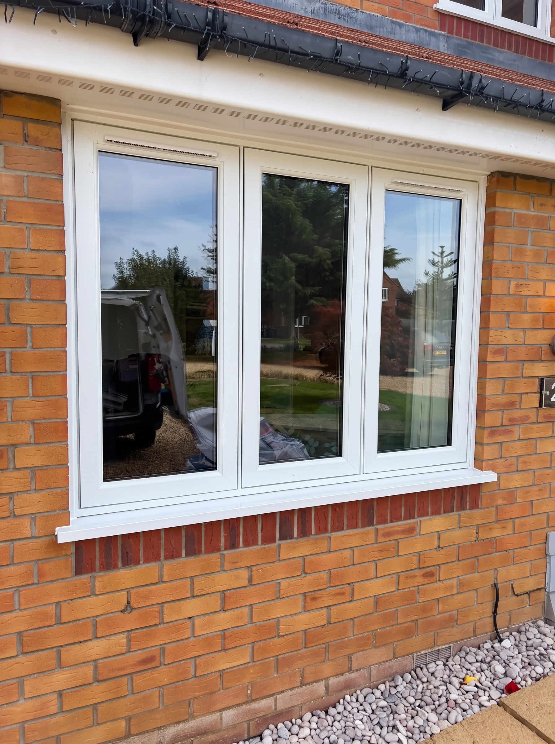 Close view of a white three-light flush UPVC window with trickle vents fitted into brickwork in Langtoft
