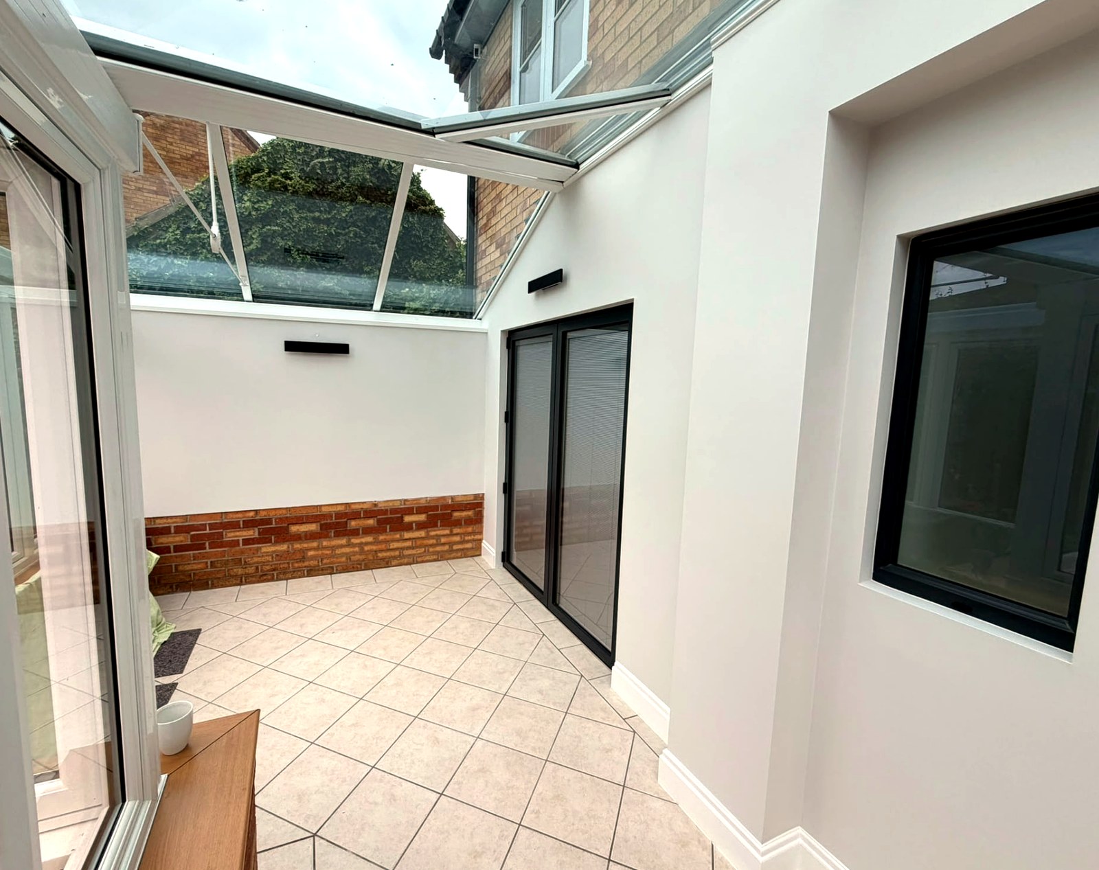 Inside a Langtoft conservatory showing white frames, tiled floor and a glazed roof