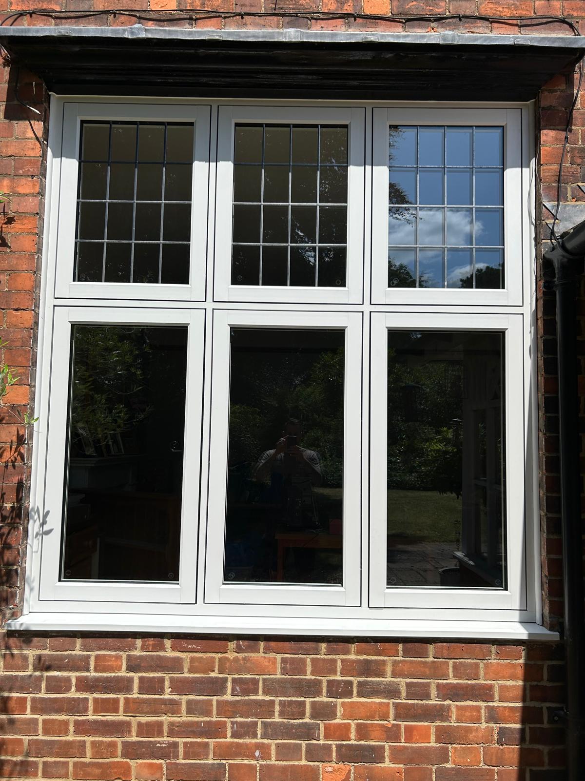White flush casement UPVC window with leaded Georgian bar toplights on a Stamford brick elevation