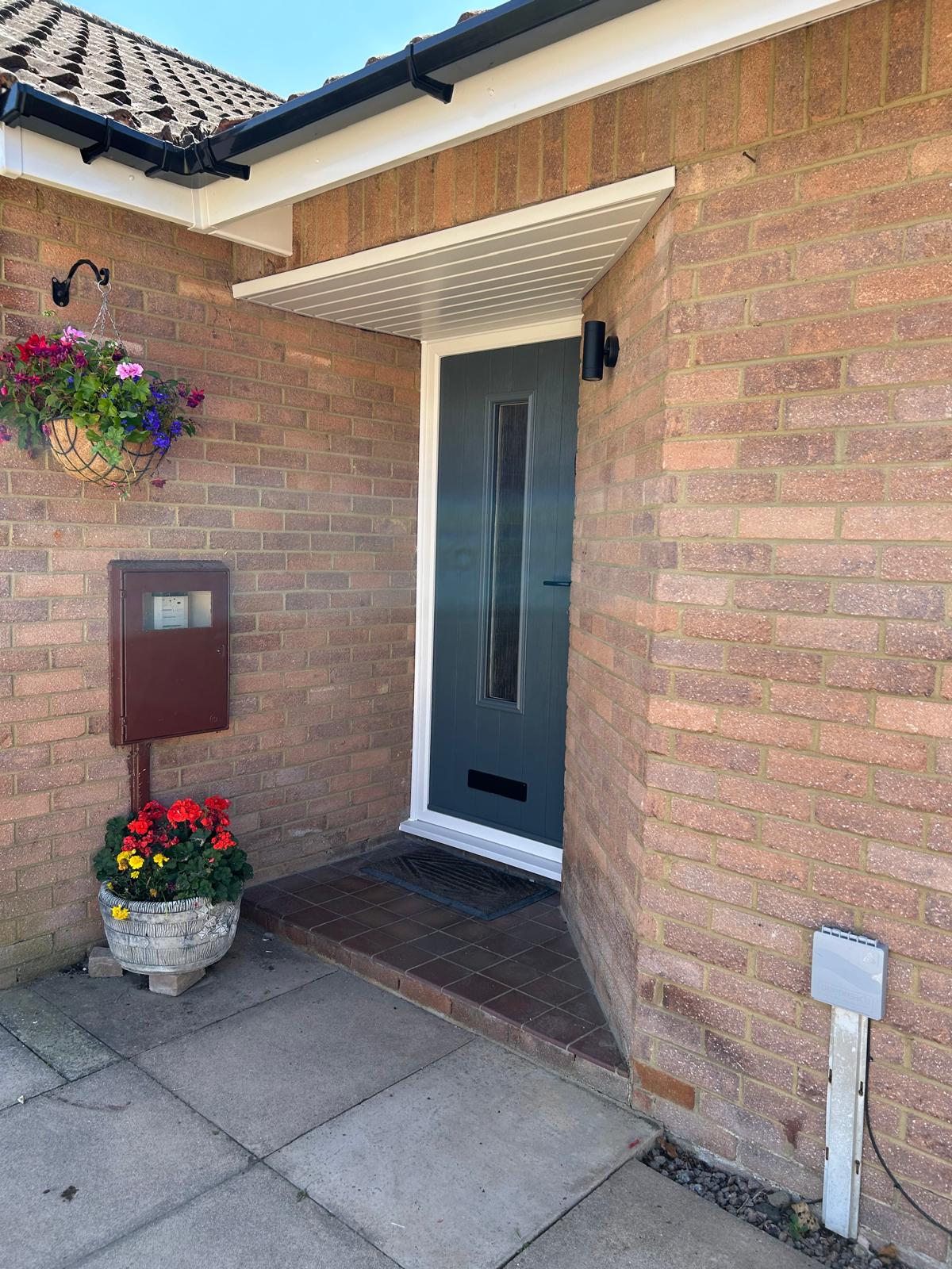 Anthracite grey composite front door with slim glazed light in a recessed brick porch in Bourne