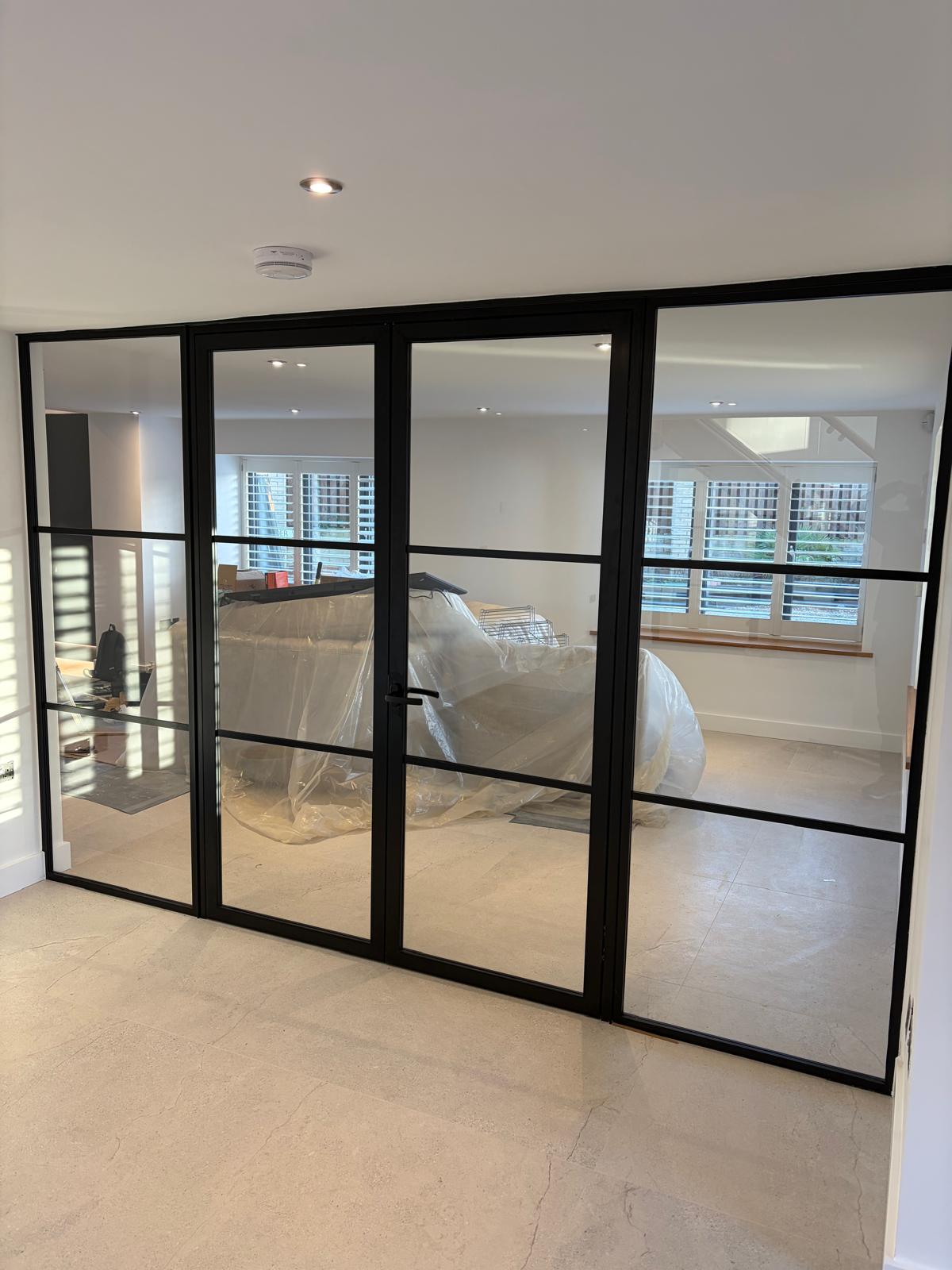 Internal black steel-look aluminium glazed screen and door dividing two rooms in a Rutland home