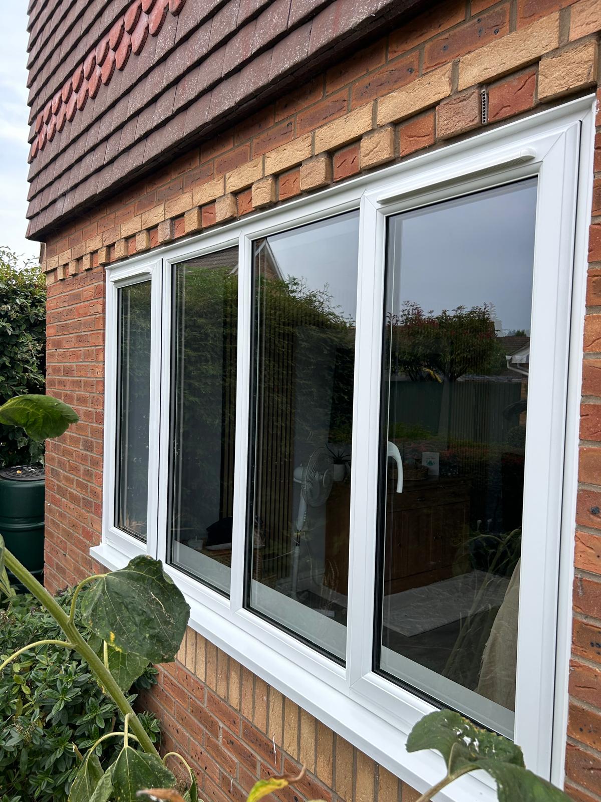 White UPVC four-light casement window run fitted to a red brick house in Bourne