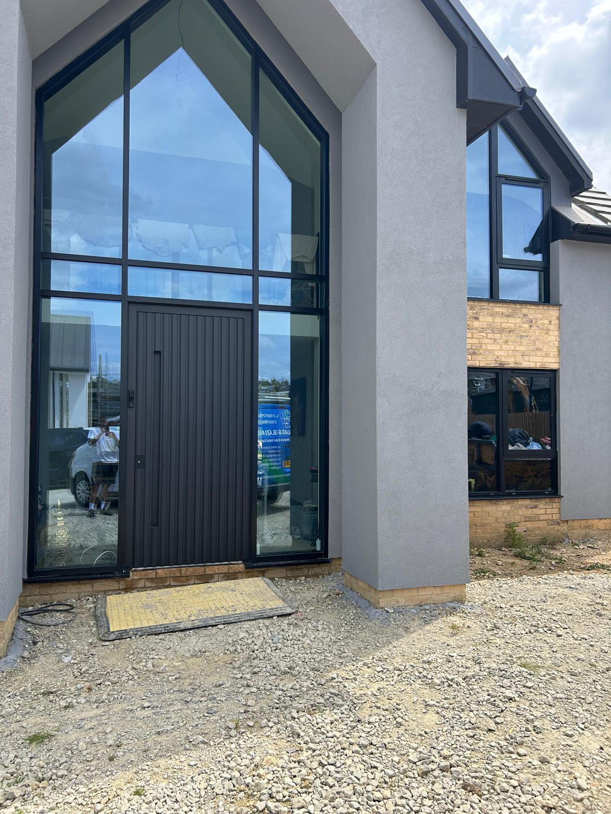 Full height apex glazed aluminium entrance screen with ribbed anthracite door on a new build home in Rutland
