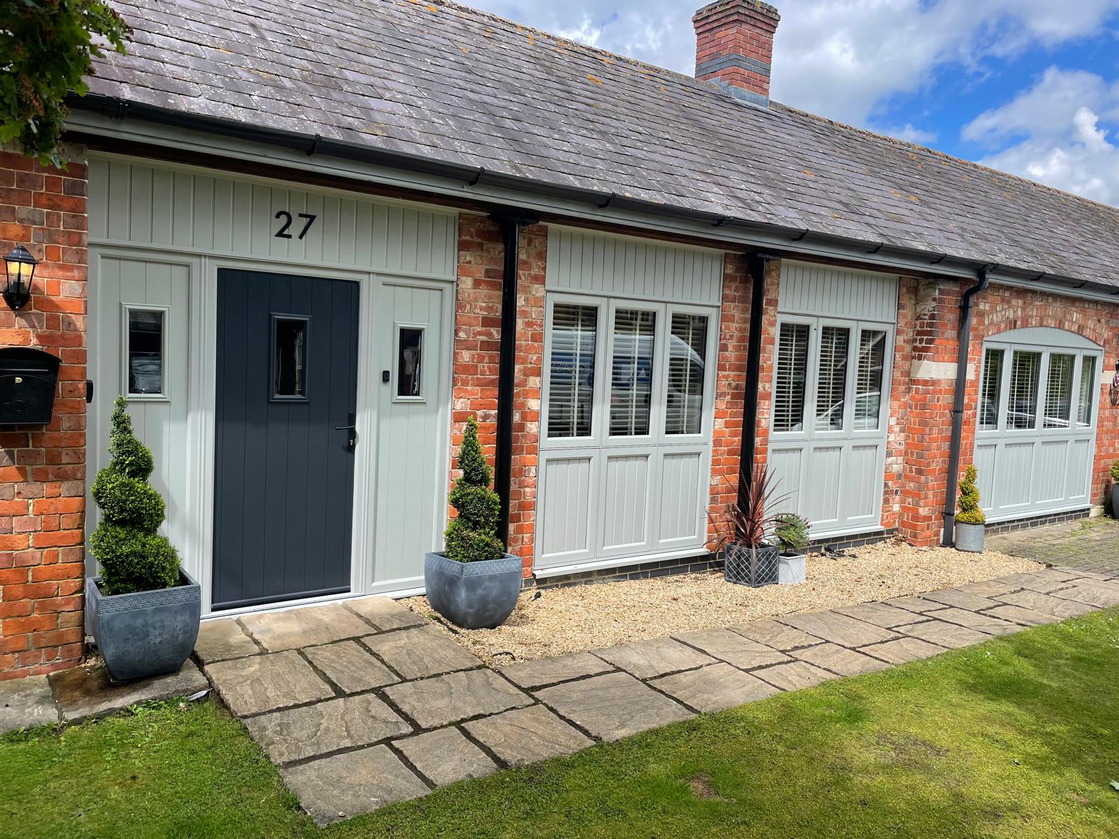 Anthracite grey cottage style composite front door with sage green panelling in a brick and slate barn conversion in Rutland