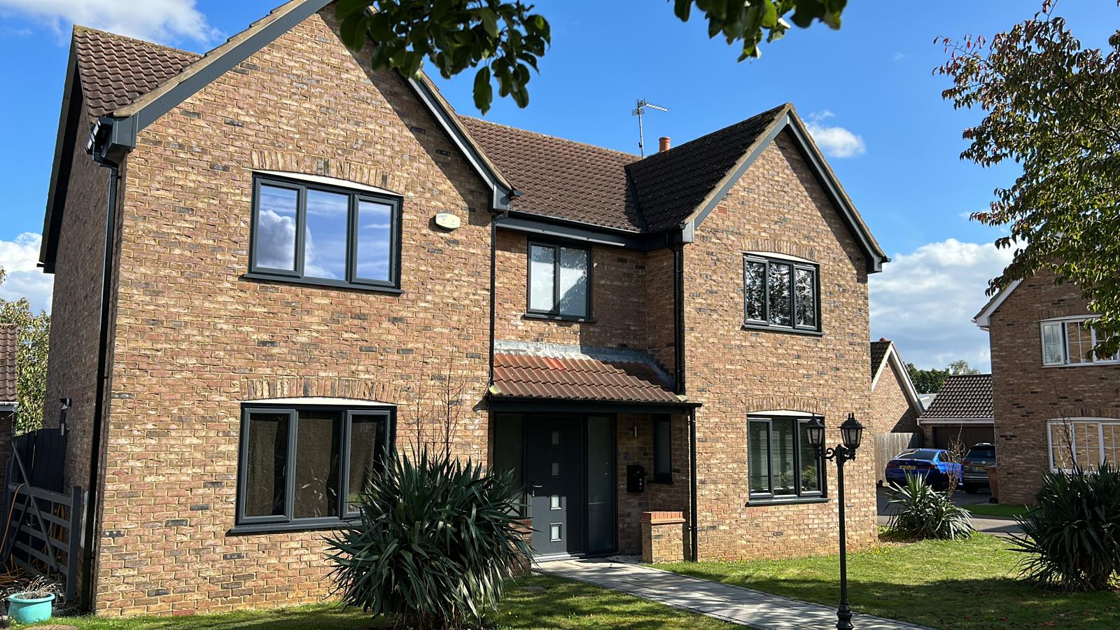 Detached brick house with new anthracite grey windows and a grey composite front door in Bourne