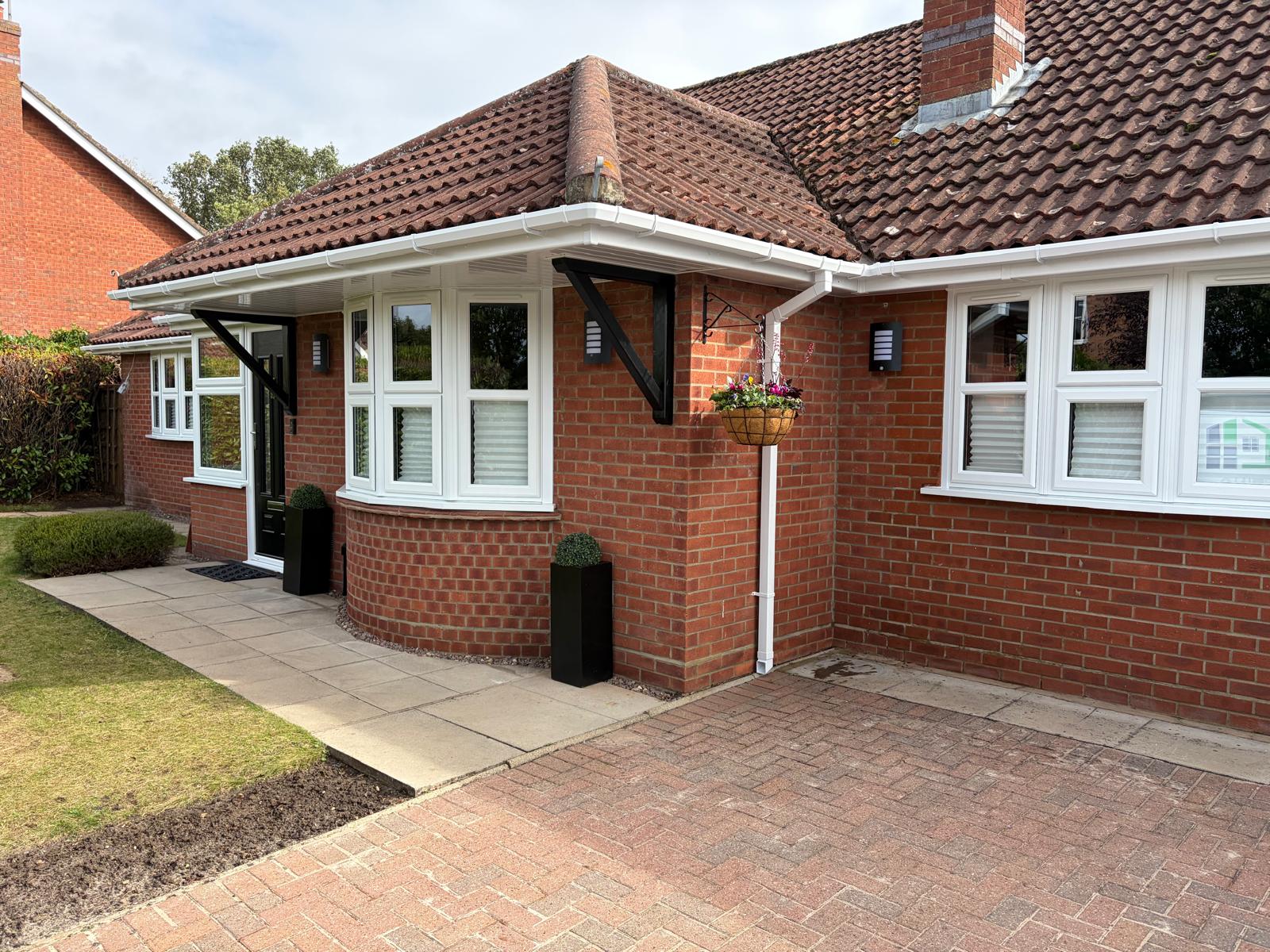 Red brick Lincolnshire bungalow reglazed with white UPVC windows, curved bay and black composite front door