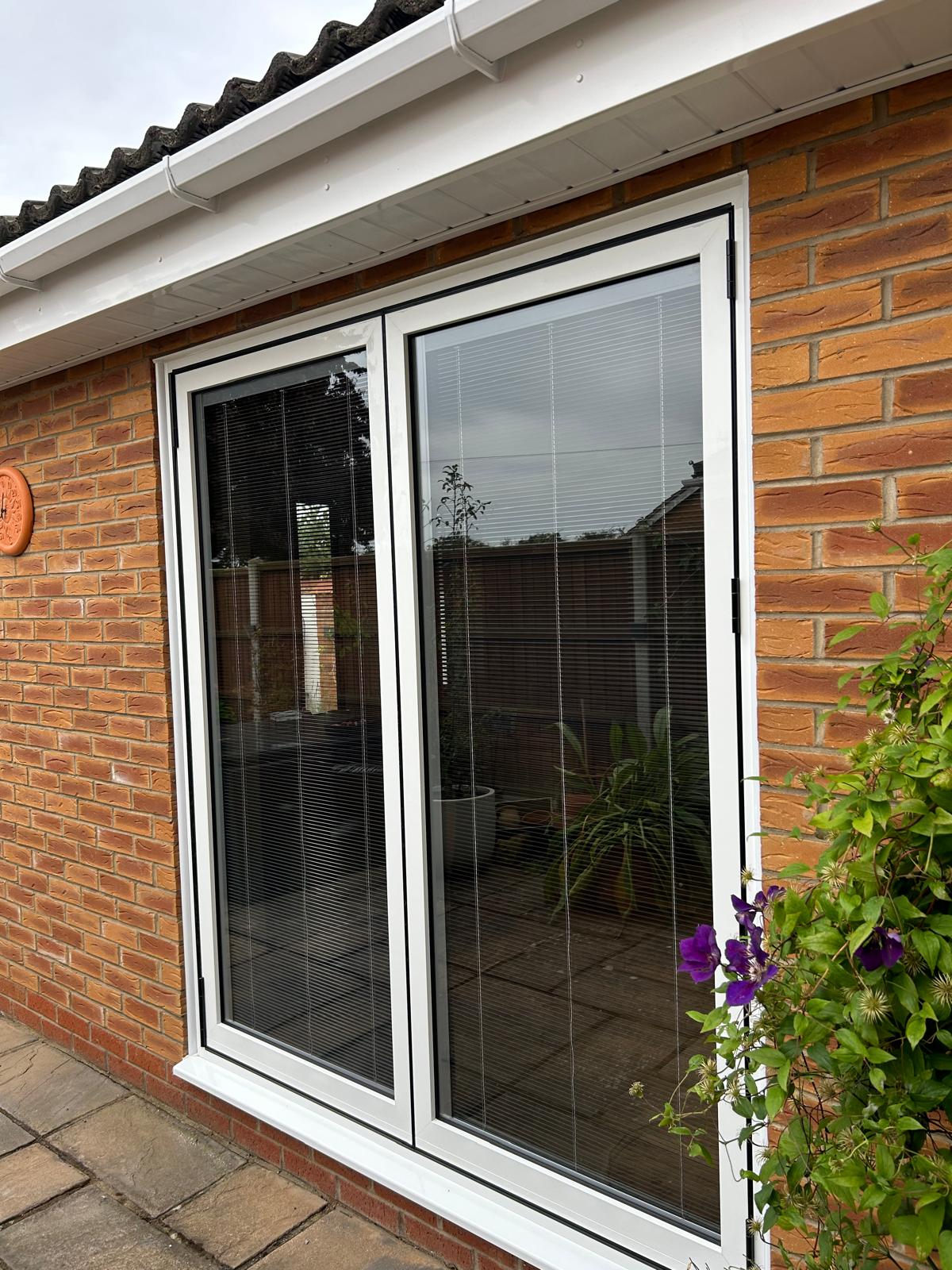 White UPVC French doors with integral blinds opening onto a patio at a Bourne bungalow