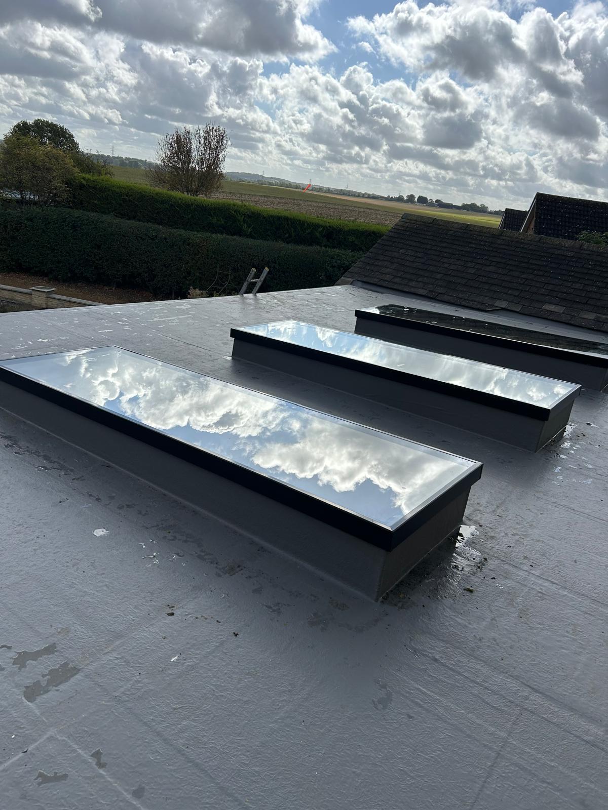Two long flat glass rooflights installed in a grey flat roof extension overlooking Lincolnshire farmland