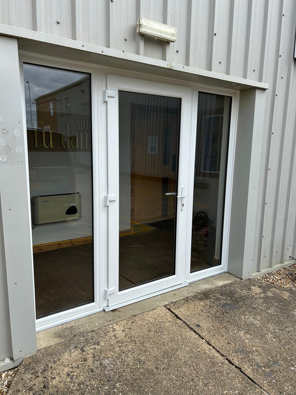 White UPVC commercial entrance door and glazed screen fitted to a steel clad industrial unit in Peterborough