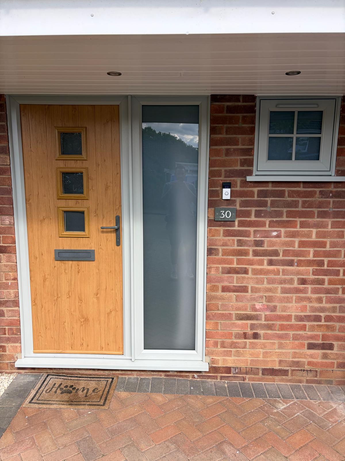 Irish oak effect composite front door with three square glazed panels and a grey side light in Stamford