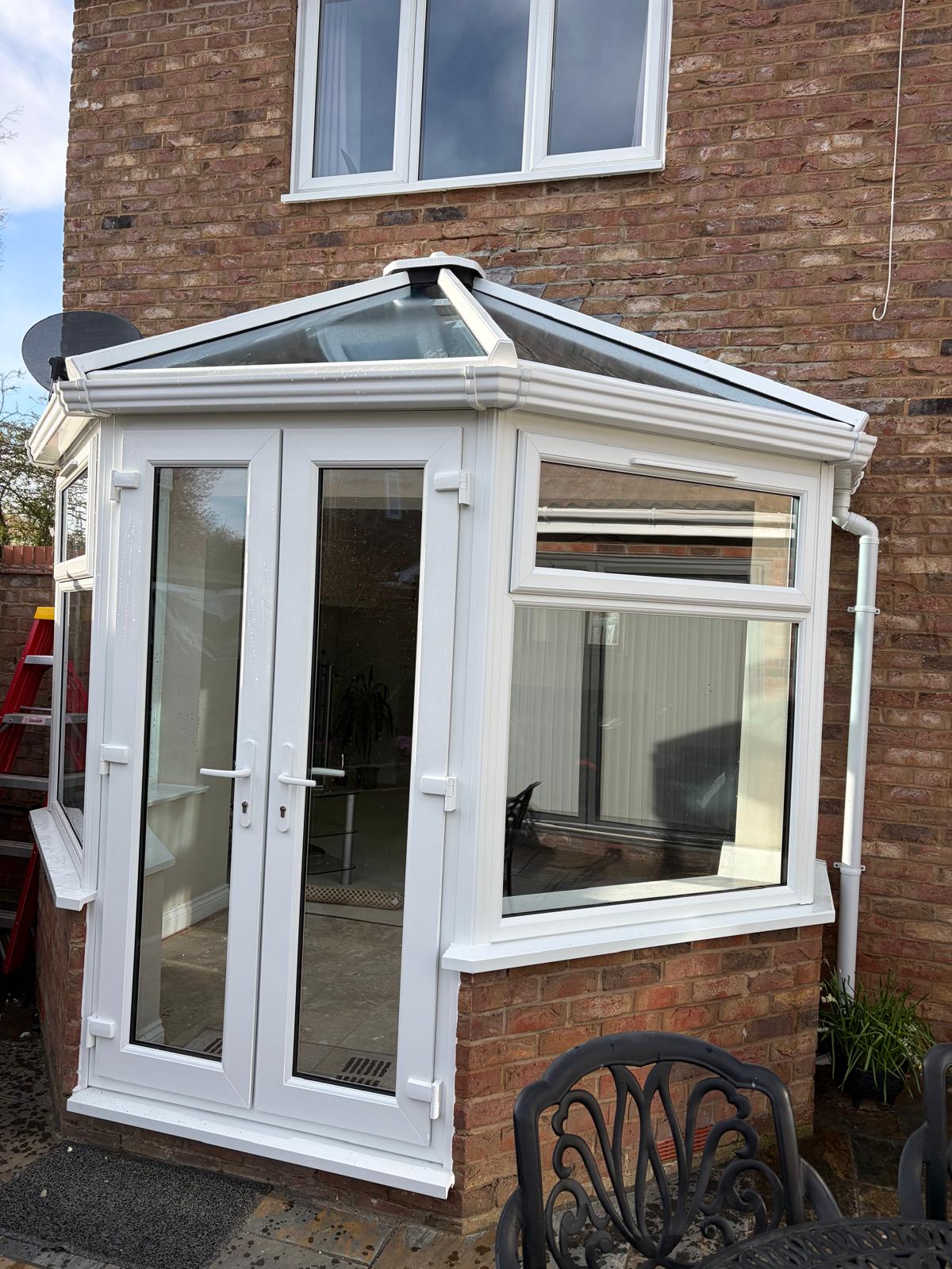 Small white UPVC conservatory with a glass roof and French doors on a red brick house in South Lincolnshire