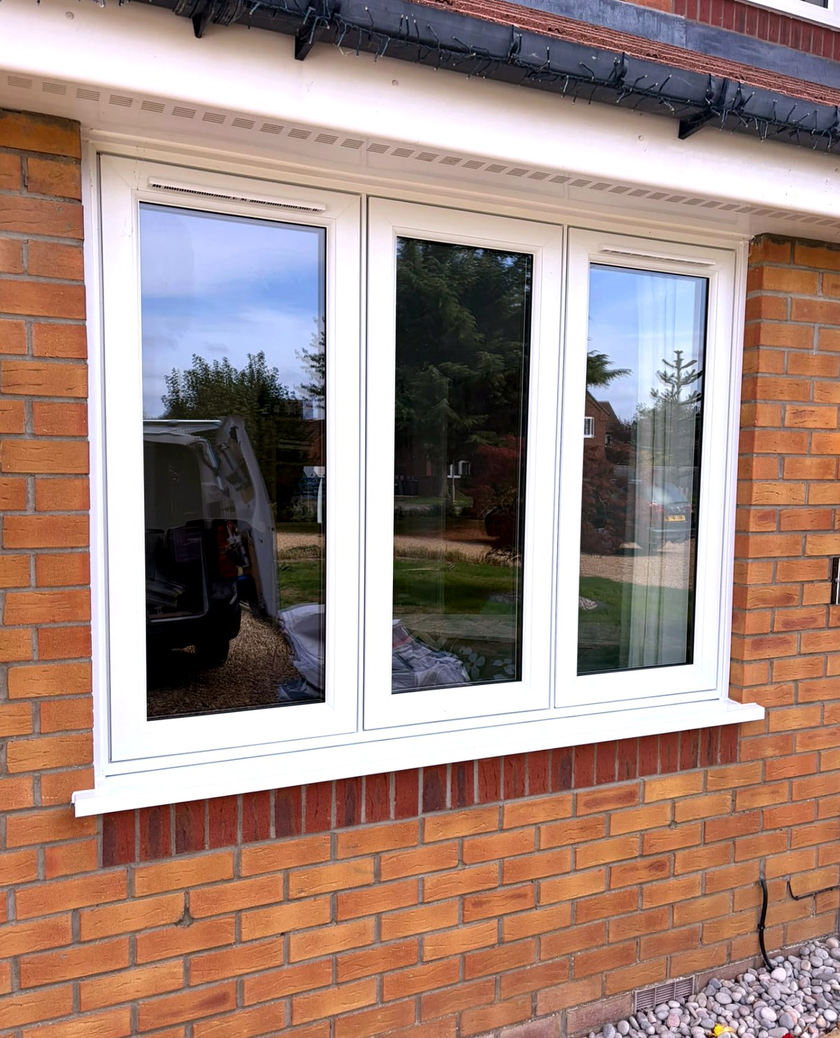 Close view of a white three-light flush casement window installed in a brick wall in Langtoft