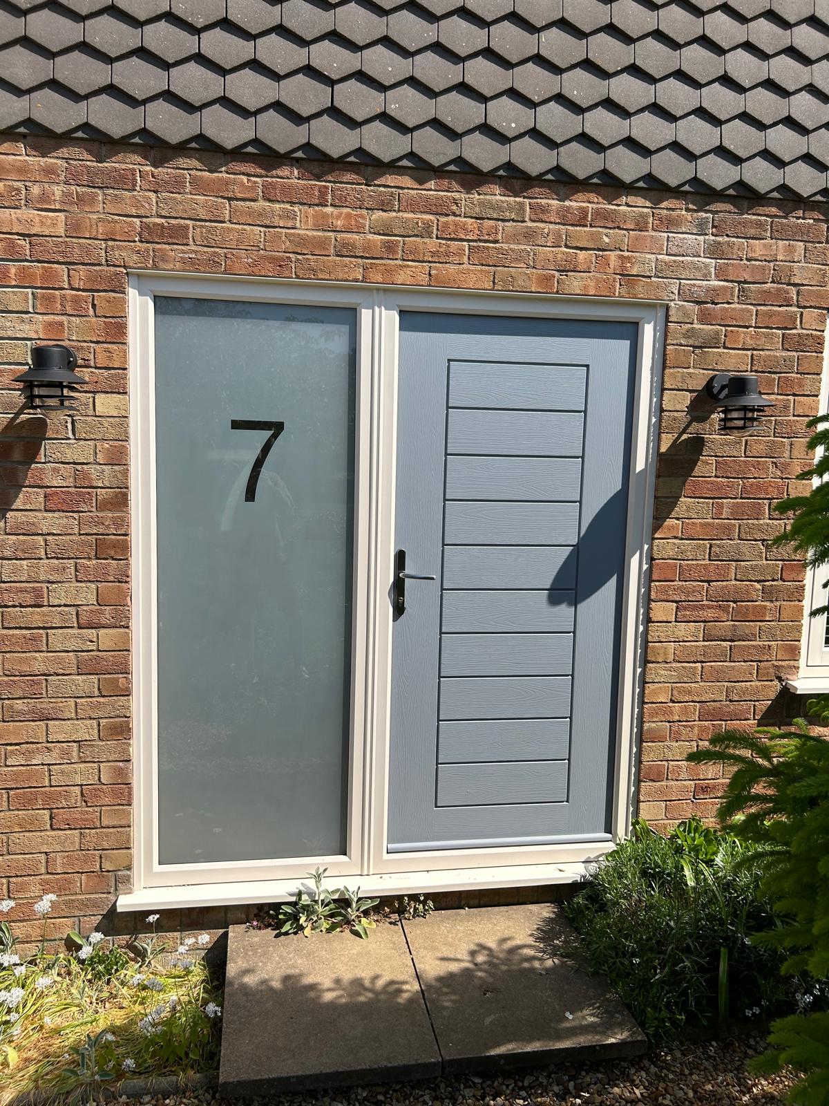 Grey composite front door with a frosted sidelight etched with the house number on a brick house in Peterborough