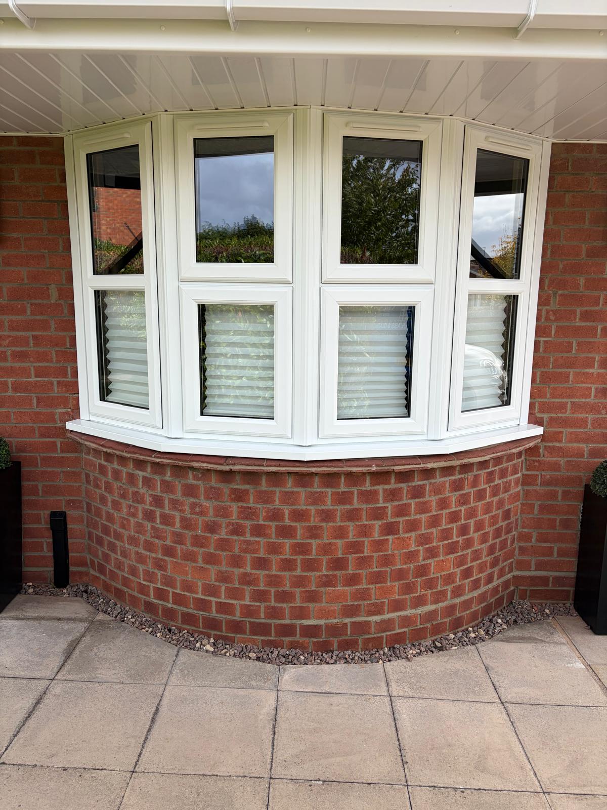 Cream UPVC bay window fitted above curved red brickwork on a Lincolnshire bungalow