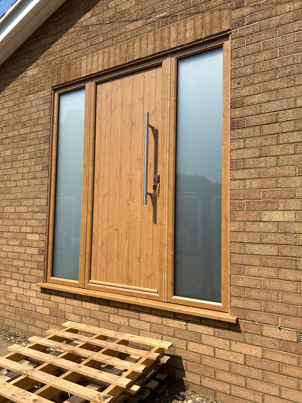 Irish oak effect composite front door with brushed steel bar handle and two obscured glazed sidelights in Rutland