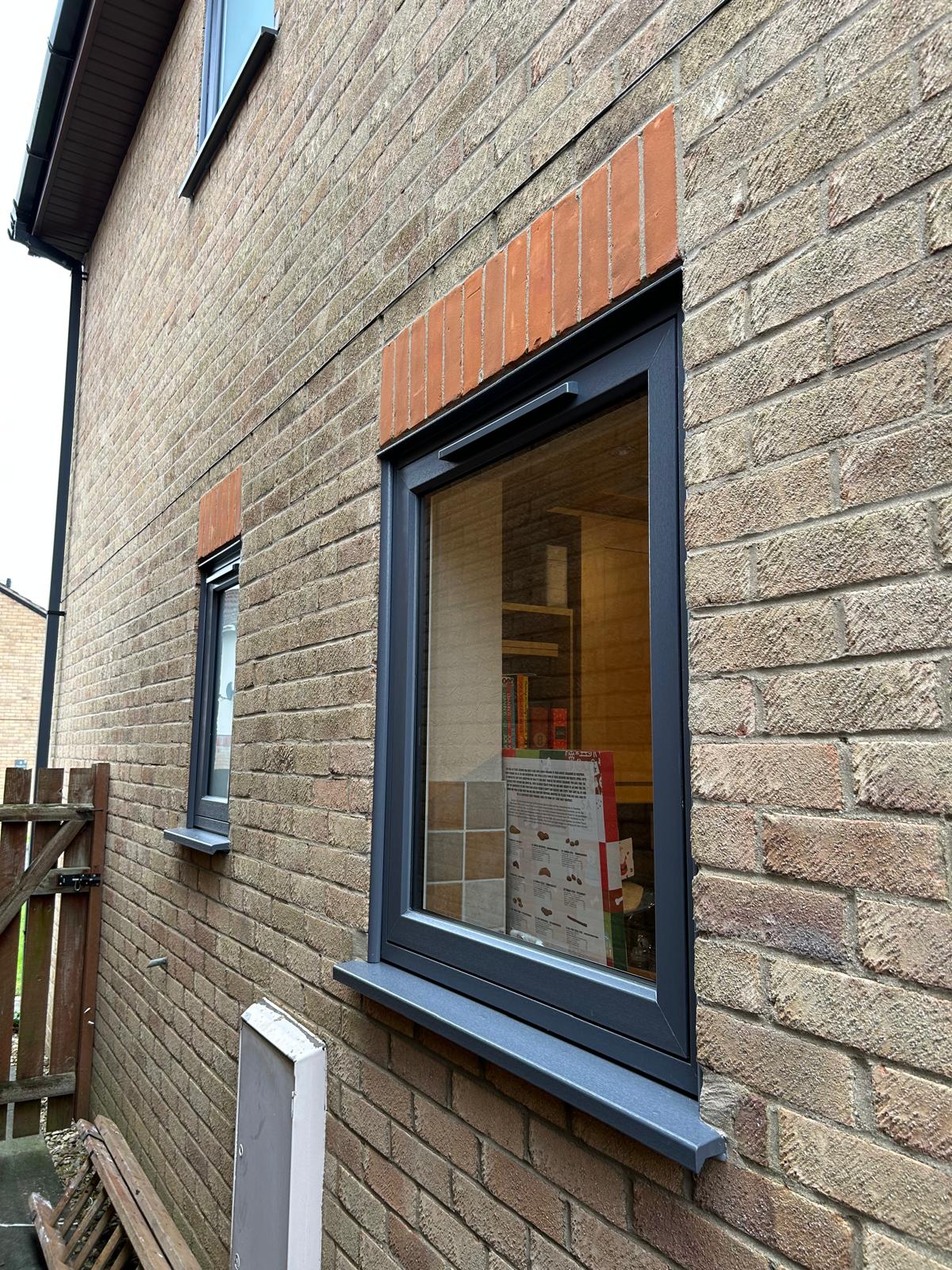 Anthracite grey window with matching cill fitted into a brick elevation in Peterborough