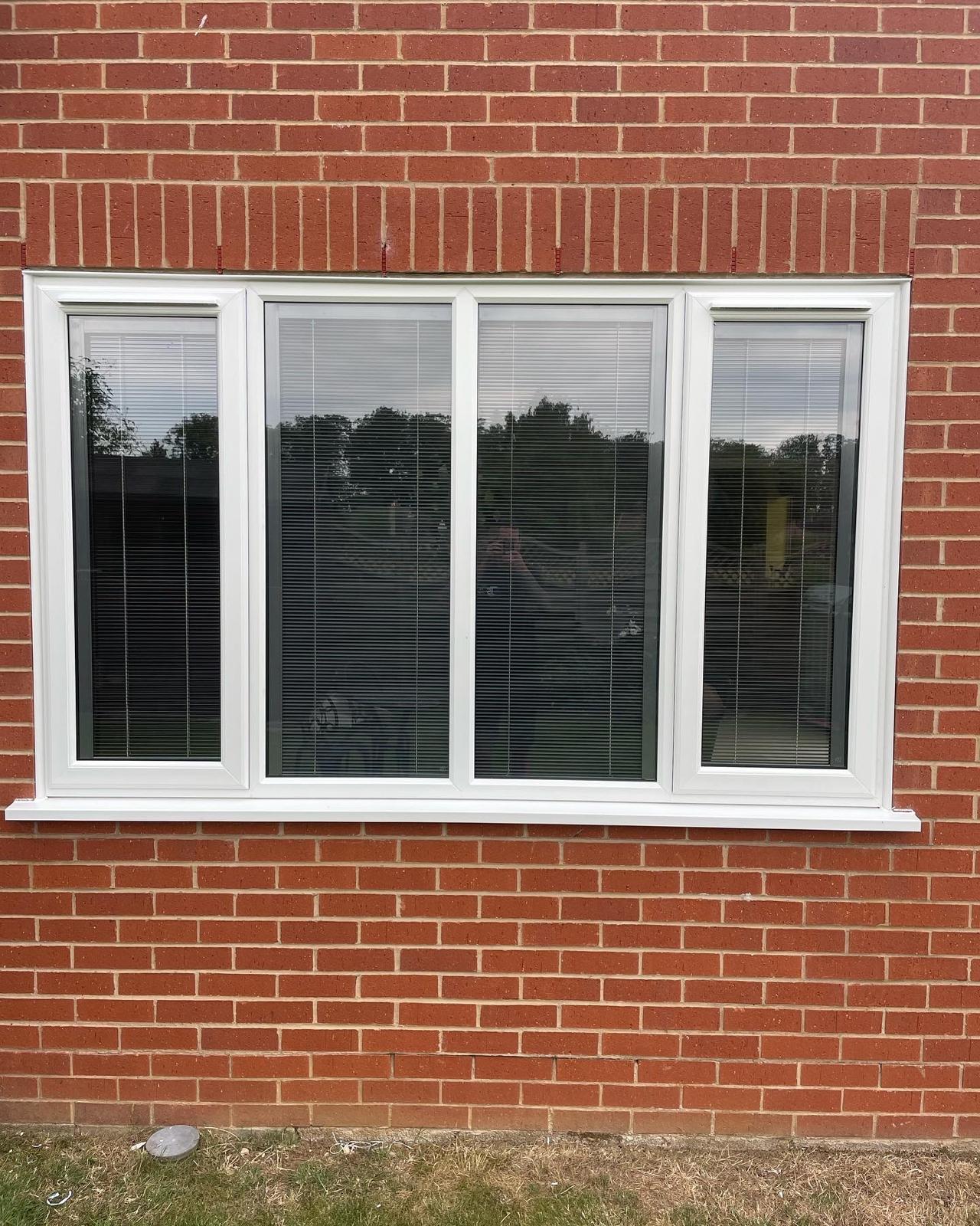 White UPVC four light casement window with integral blinds in a red brick wall in Peterborough