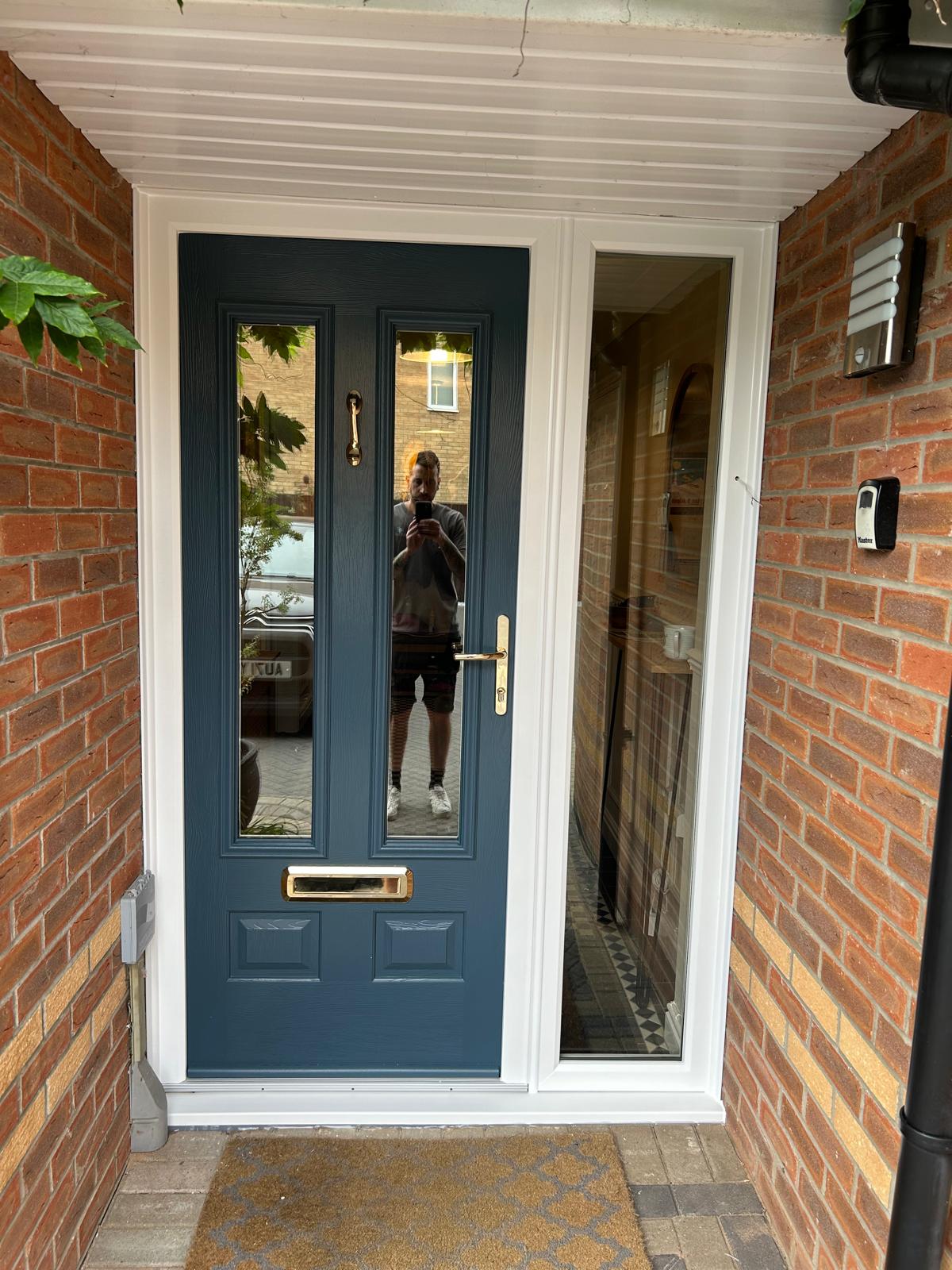 Deep blue composite front door with polished brass furniture and a full height glazed sidelight in Stamford