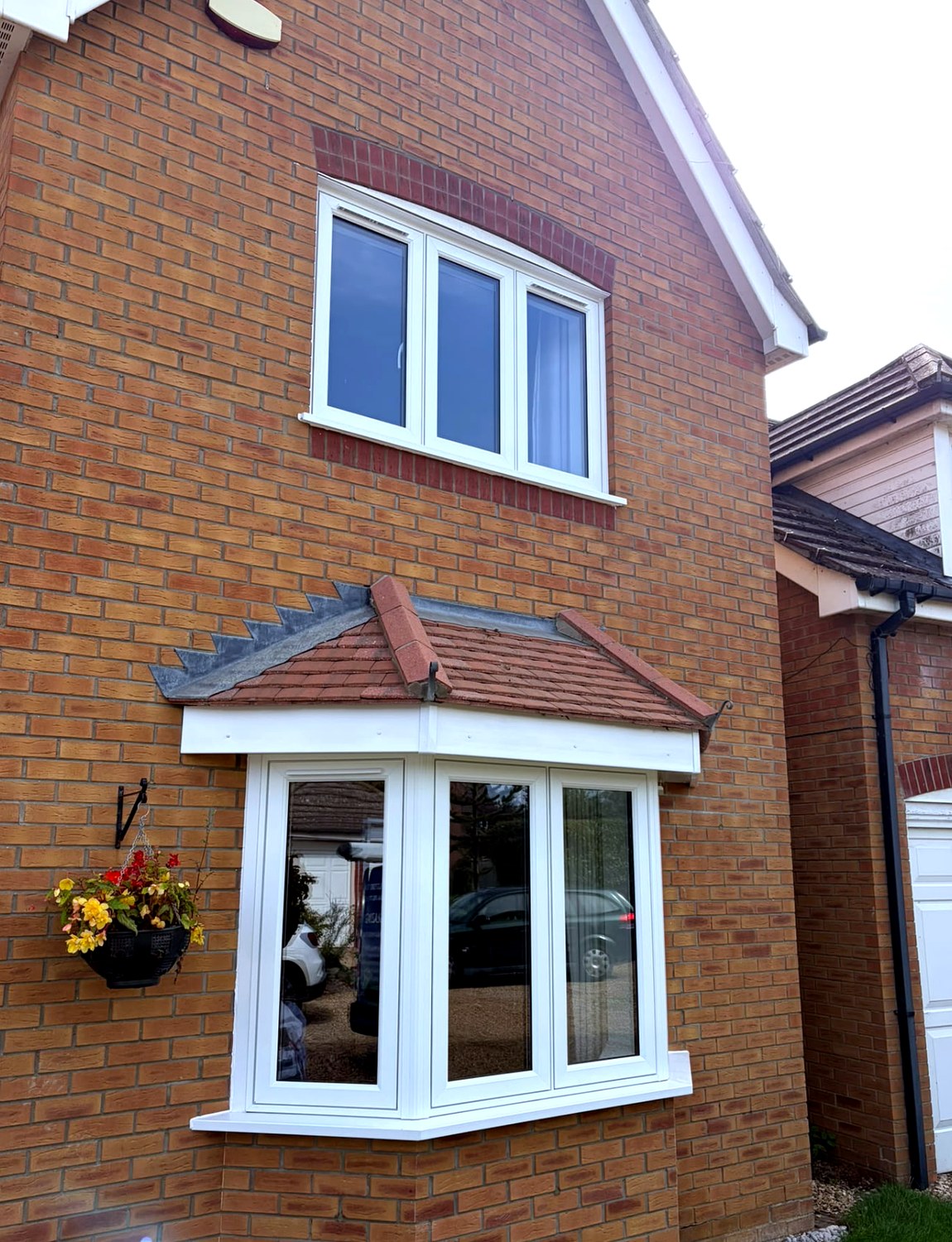 White flush casement bay window fitted beneath a tiled canopy on a red brick home in Langtoft