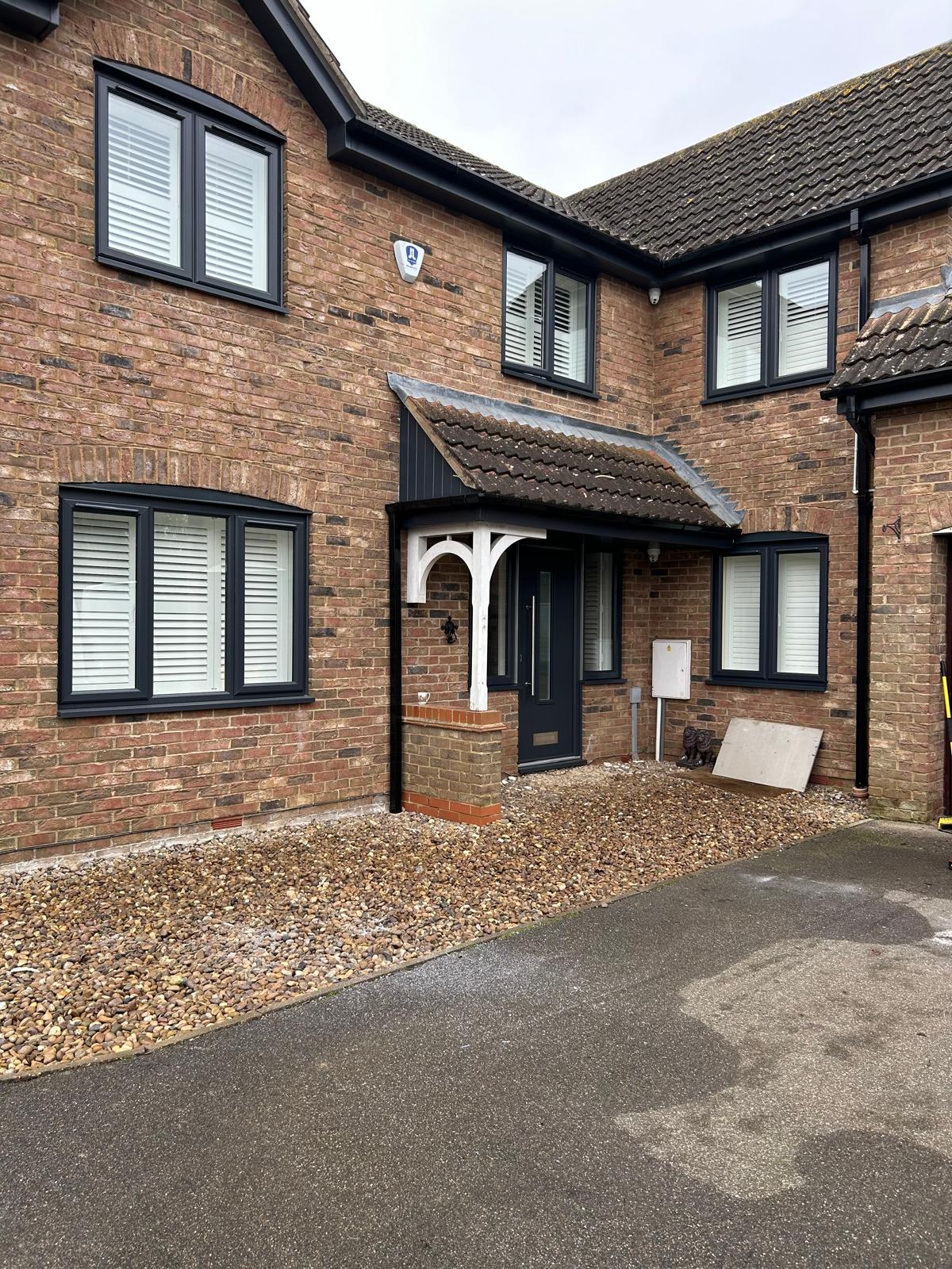 Red brick house with anthracite grey windows and matching front door replaced across the full elevation in Rutland