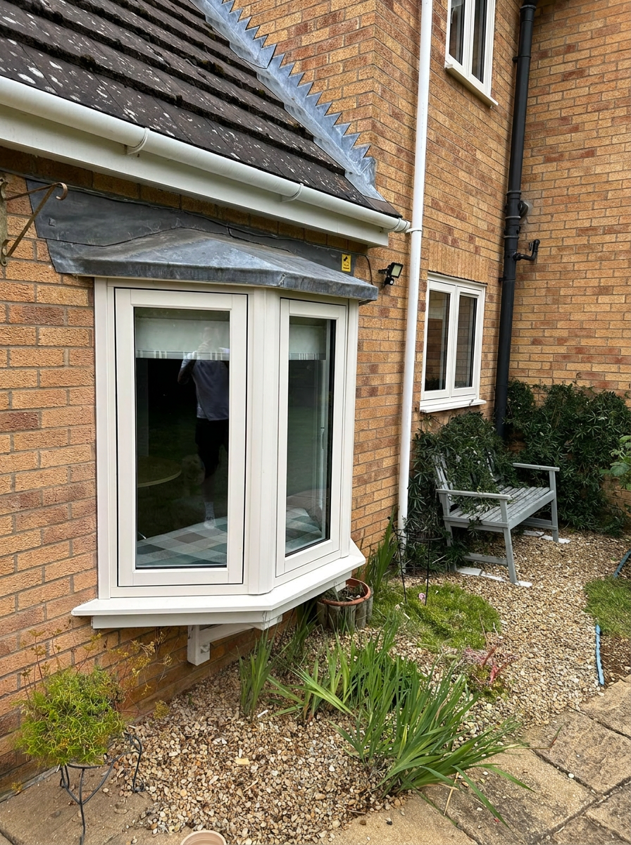 Cream bay window replacement on a Rutland brick house beneath a lead canopy