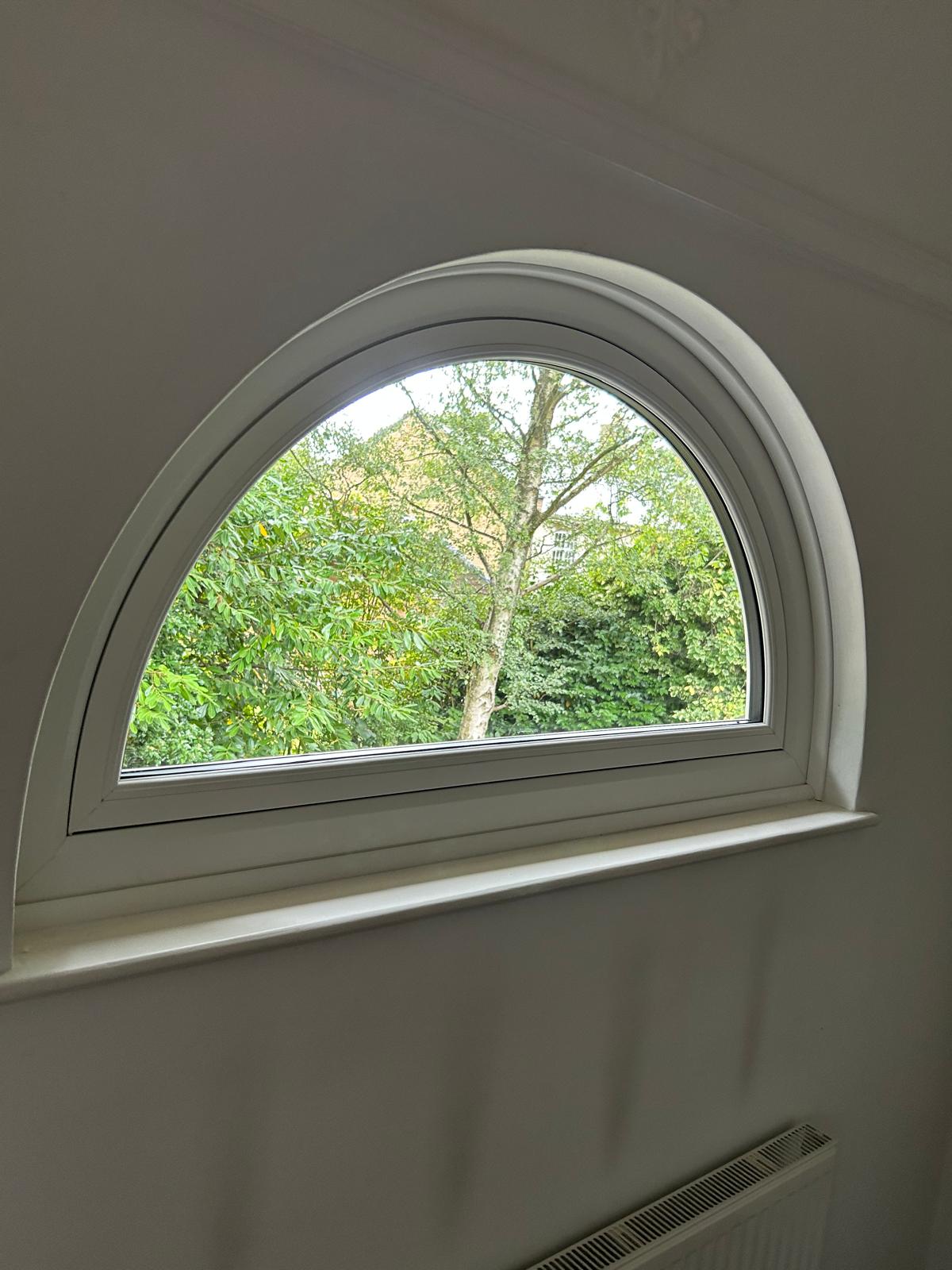 White half-round arched UPVC window fitted into a plastered interior reveal in a Stamford property