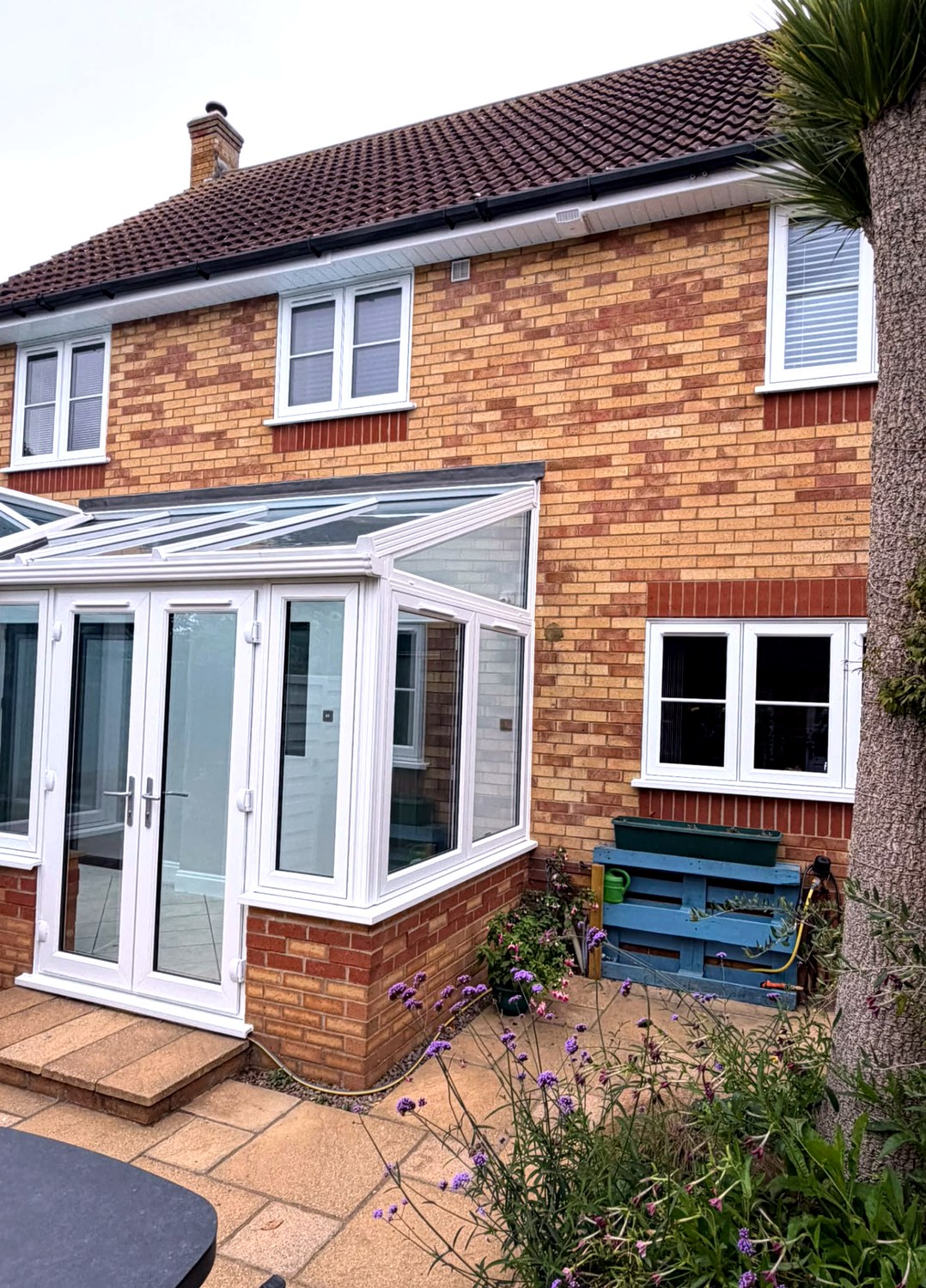 Garden view of a white UPVC conservatory with glazed roof on a brick home in Langtoft