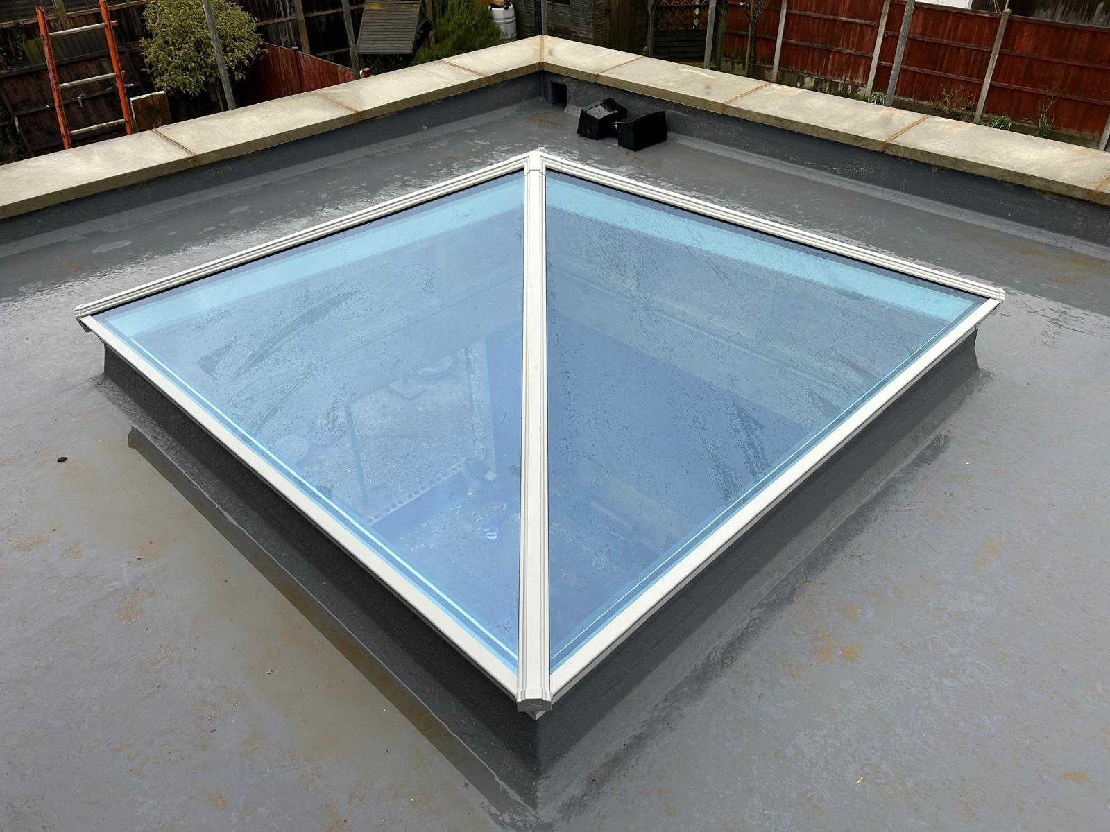 White hipped glass roof lantern installed on a grey flat roof extension in Peterborough