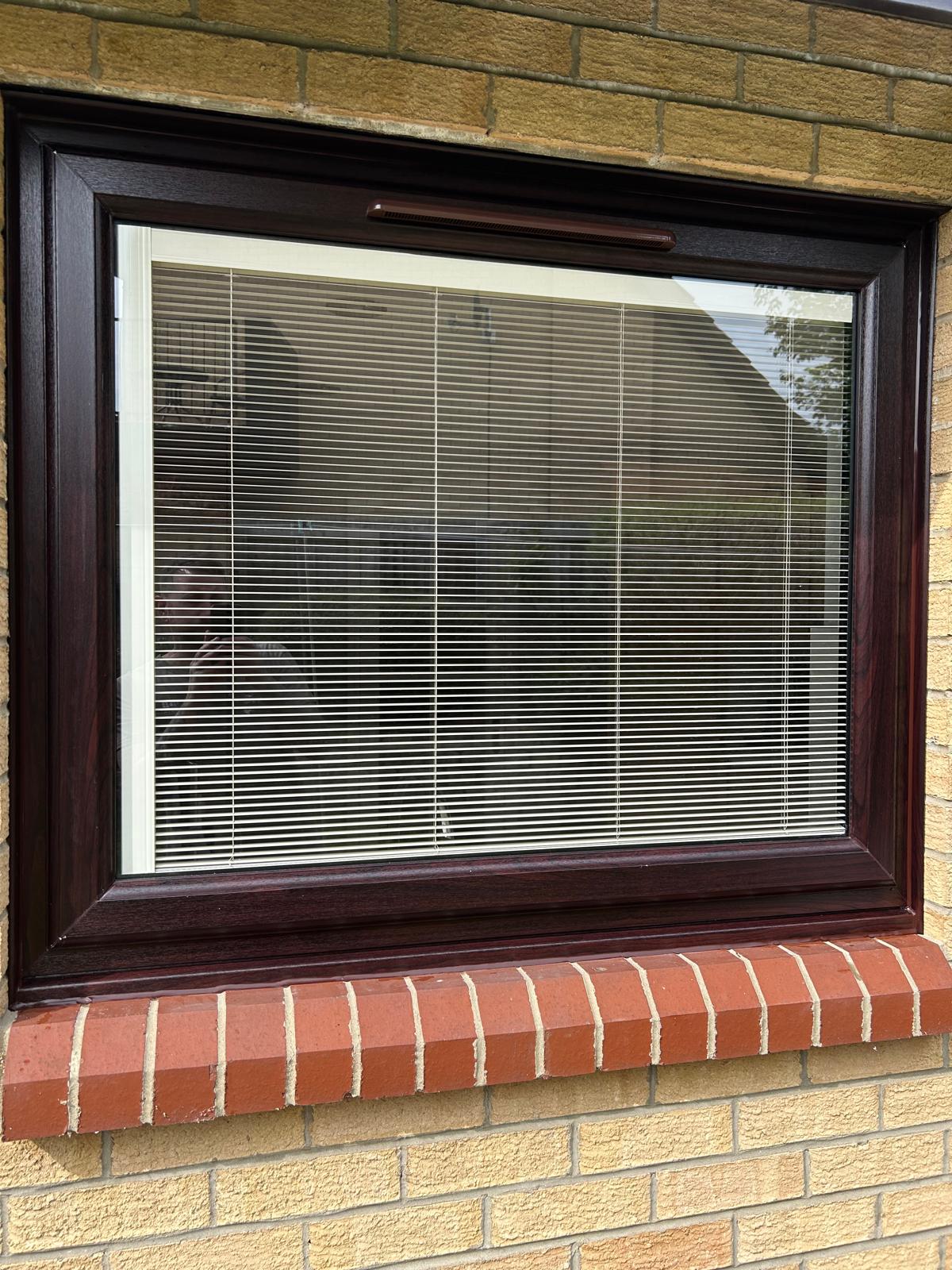 Rosewood UPVC picture window with integral blinds above a red brick cill in Peterborough