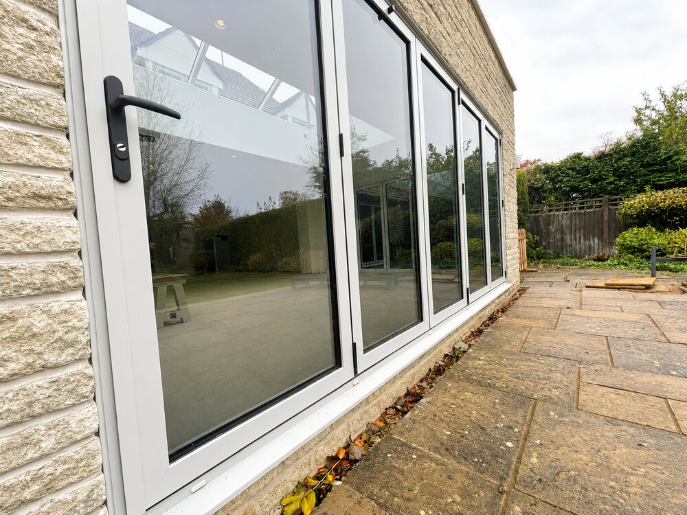 White aluminium bi-fold doors exterior view on a Rutland stone extension