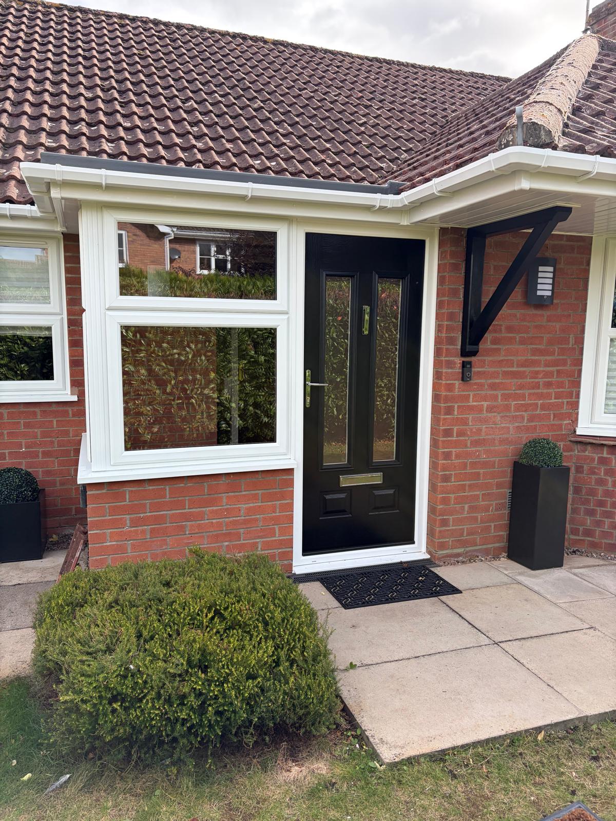 Black composite front door with brass furniture and a white UPVC porch window on a Lincolnshire bungalow